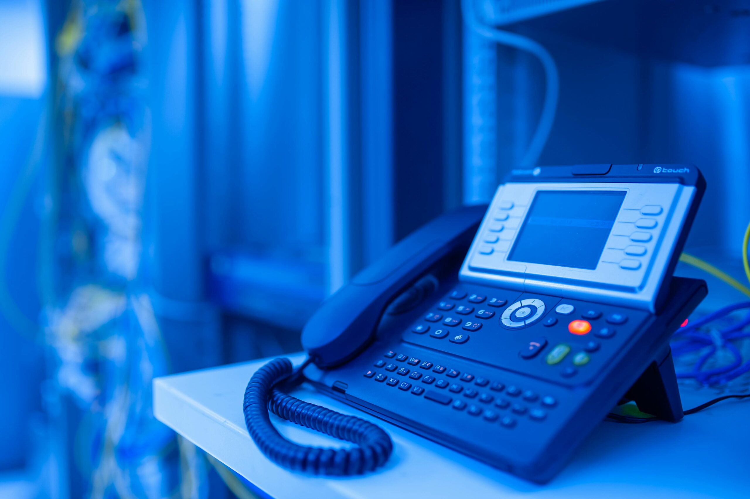 Services Close-up of a modern office phone in blue lighting. Ideal for tech and business themes.