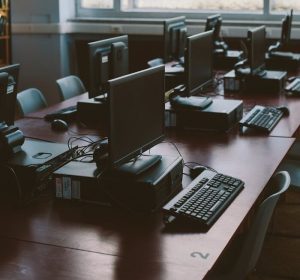 Spacious computer lab with rows of monitors and keyboards in a sunlit room.